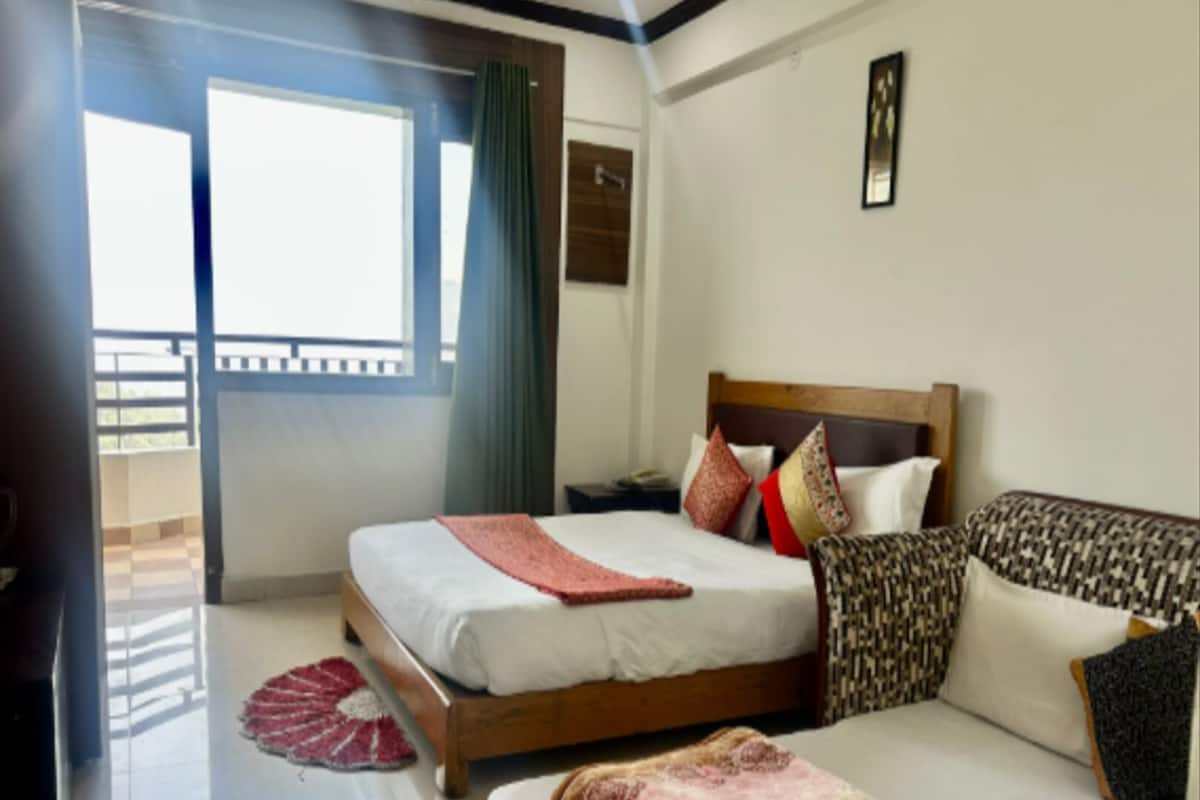 Ein Hotelzimmer mit Bett, Sofa, Fenster und Balkon.