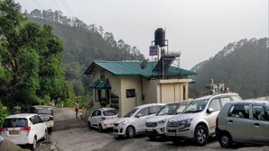 Un hôtel doté d’un toit végétalisé, d’une citerne d’eau et de plusieurs voitures garées.