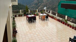 Une terrasse avec une table et des chaises, des plantes en pot et une chaîne de montagnes en arrière-plan.