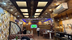 Un restaurante con techo estampado, paredes de madera y una pantalla de televisión mostrando un partido deportivo.