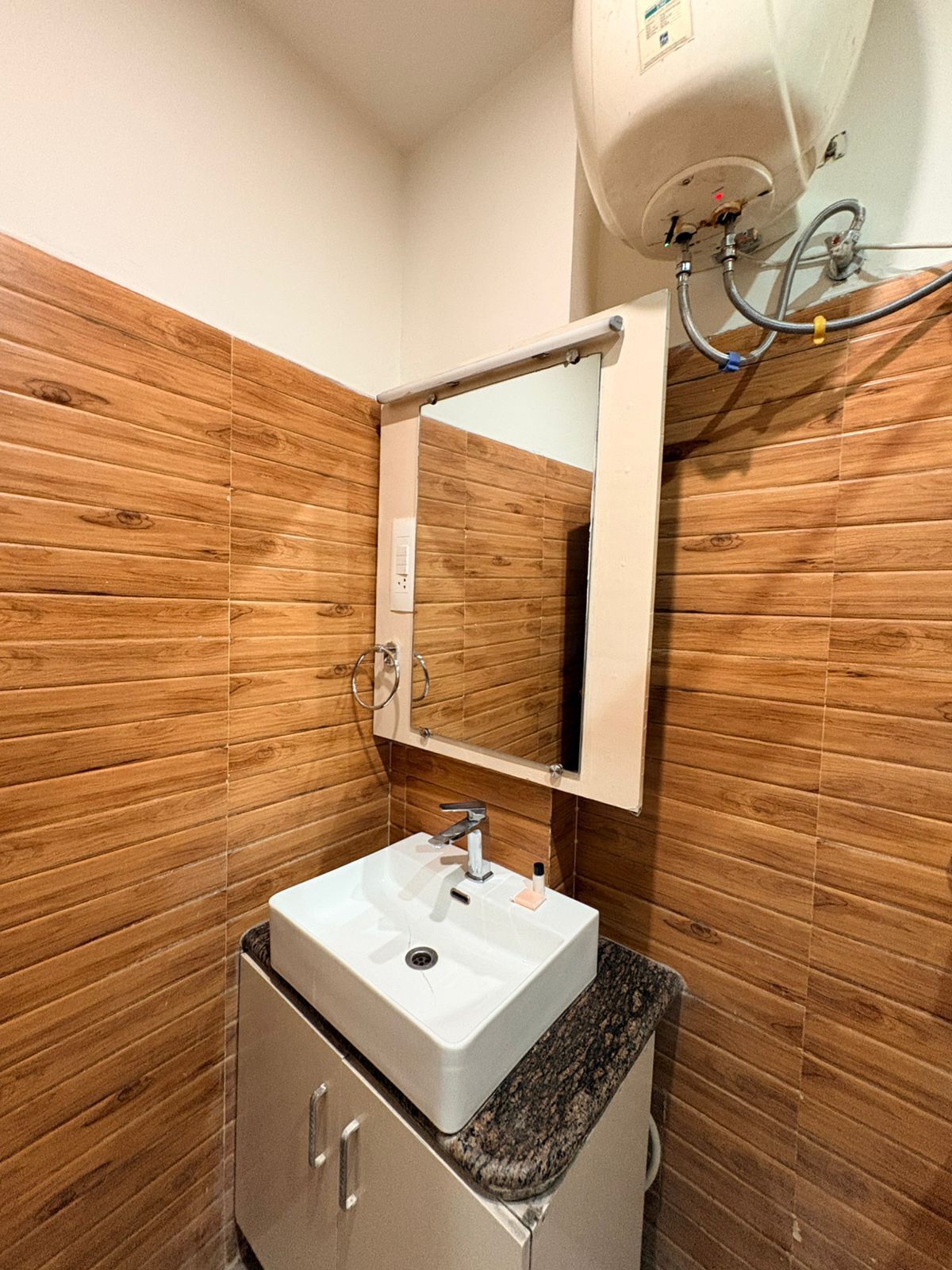 A bathroom with wooden panel walls, a white sink with a mirror, and a towel rack.