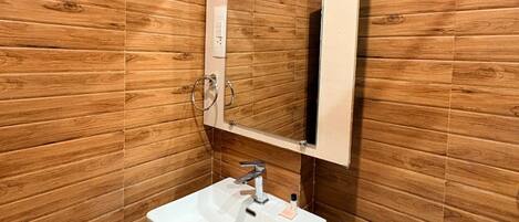 A bathroom with wooden panel walls, a white sink with a mirror, and a towel rack.