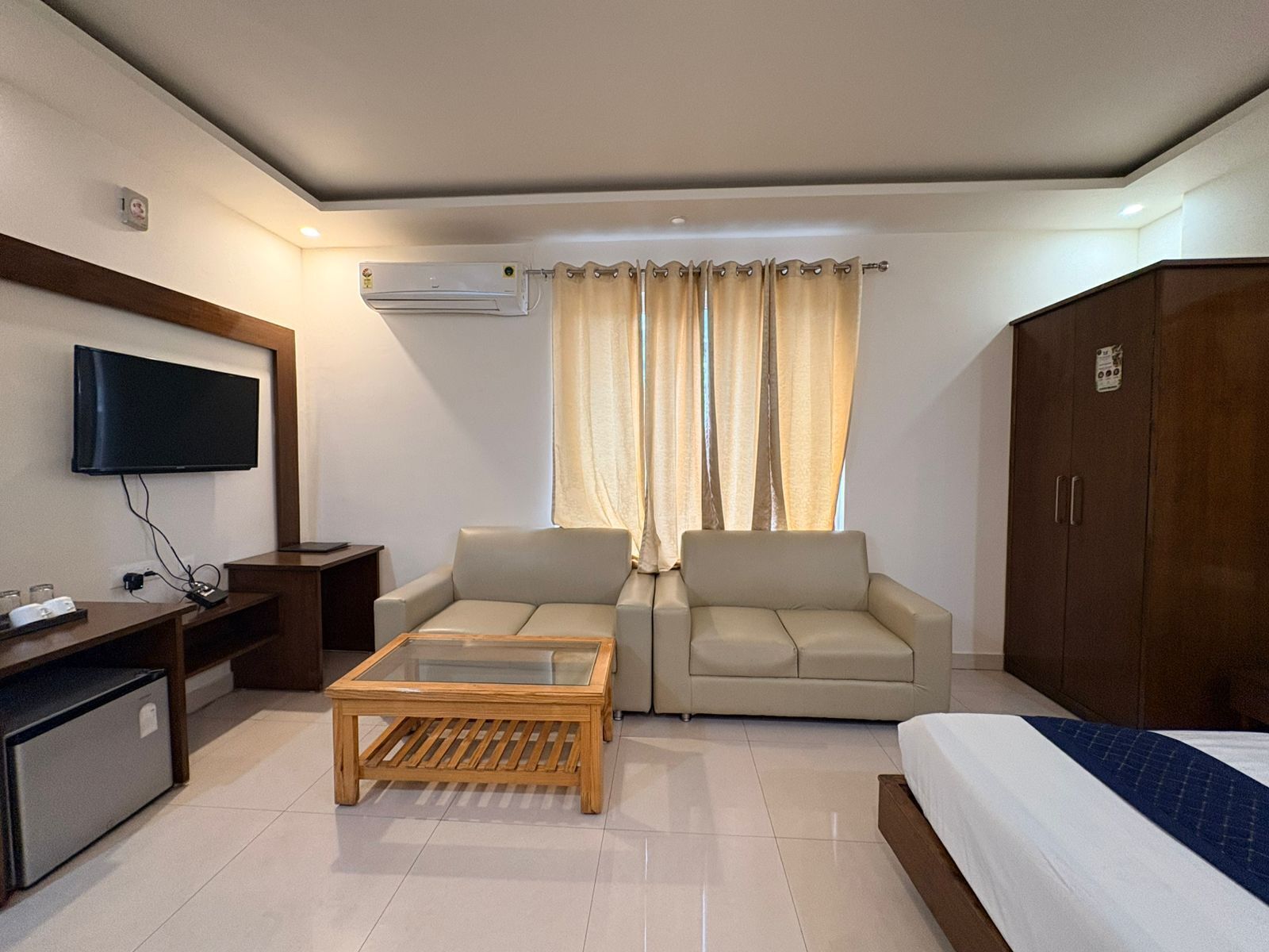 Une chambre d’hôtel comprenant un lit, un canapé, une table basse, une télévision et une armoire.