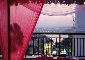 A balcony with a view of a cityscape at dusk. - Hotel Bliss Ganga  (Rishikesh)