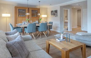 Un salon moderne comprenant un coin repas, des meubles en bois et un téléviseur à écran plat.