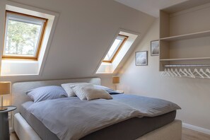 Une chambre à coucher comprenant un lit, deux lampes de chevet, une table de chevet, une fenêtre et une bibliothèque intégrée.