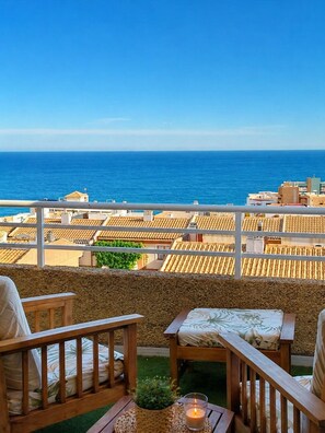 A balcony with a view of the sea, wooden furniture, and a candle. - Costamar, bungalow familiar con terrazas y piscina a 5 minutos de la playa (Los Arenales del Sol)