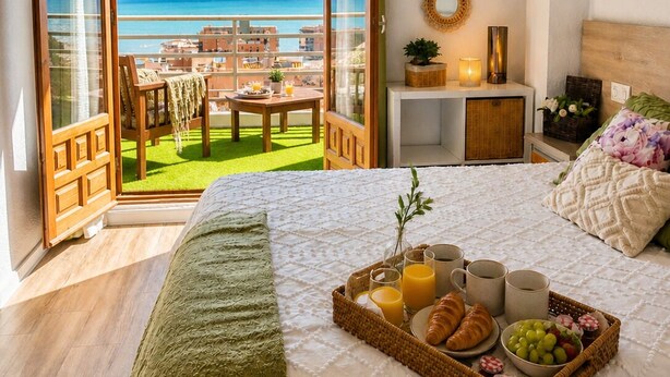 Ein Schlafzimmer mit Balkon, einem Bett mit Frühstücksbrett und Meerblick.