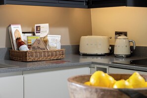 A kitchen with a basket of food items, a toaster, and a coffee maker. - Church Alley House (Cheltenham)