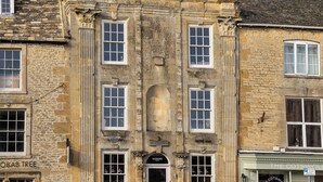 Un edificio histórico con numerosas ventanas, un arco de entrada destacado y letreros que indican 'Massimo' y 'Wine Bar'.