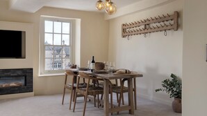 Comedor con mesa, sillas, chimenea, estante para vinos empotrado y televisor.