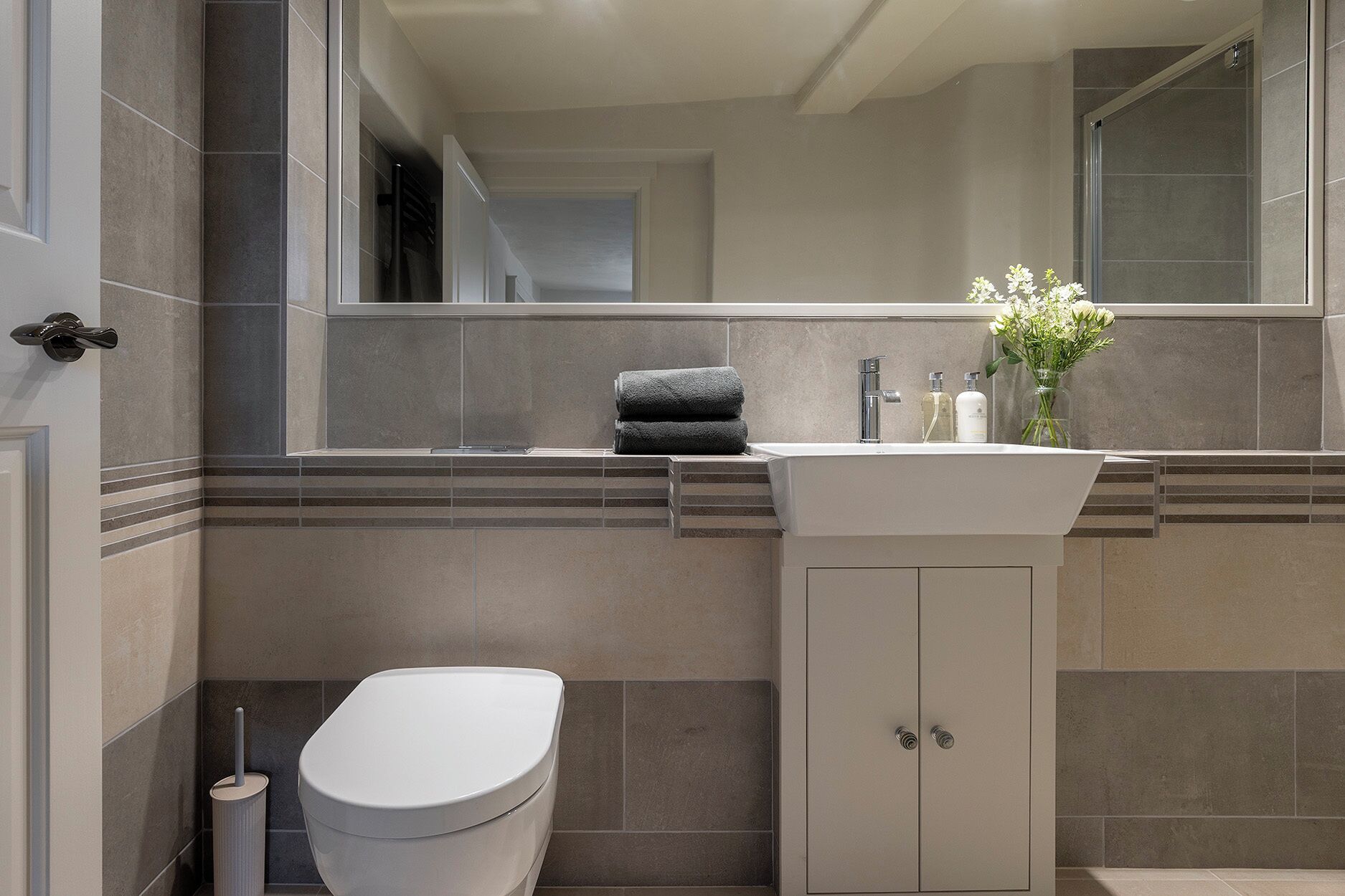 A bathroom with a toilet, sink, and mirror.