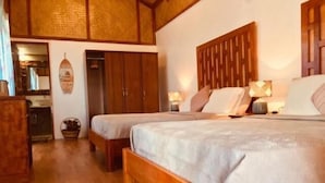 A room with two wooden beds, a wooden wardrobe, and a small kitchen area.