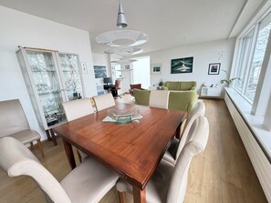 A modern dining area with a wooden table, cushioned chairs, a glass cabinet with dishes, and a green sofa in the background. - Modern apartment centrally located in Reykjavik (Reykjavík)