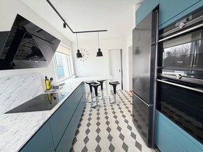 A modern kitchen with a black refrigerator, a marble countertop, and a checkered floor. - Modern apartment centrally located in Reykjavik (Reykjavík)