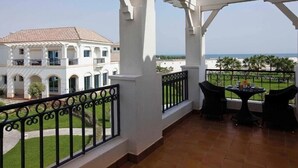 A covered balcony with a view of a white building and the sea. - Move on Beach Resort Al Khobar (Al Khobar)