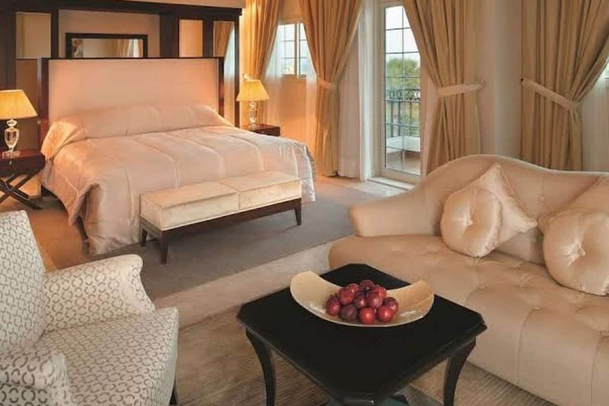 Ein Hotelzimmer mit Bett, einer Couch, einem Sessel und einem Tisch mit Obst.