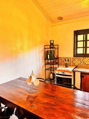 A kitchen with a wooden table, a coffee machine, a stove, and a window with a view.