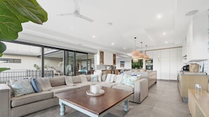 Una sala de estar moderna con un sofá seccional, una mesa de centro y una zona de cocina con armarios blancos y una encimera.