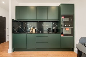 Eine moderne Küche mit dunkelgrünen Schränken, einer schwarzen Arbeitsplatte und einem eingebauten Backofen.