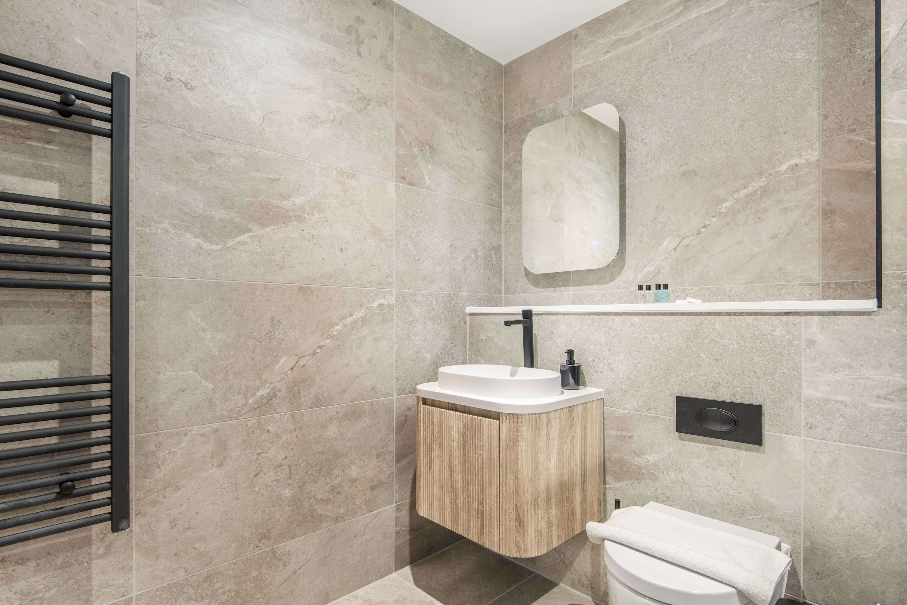 Een moderne badkamer met een vrijstaand wastafelmeubel, een handdoekhouder en een spiegel.