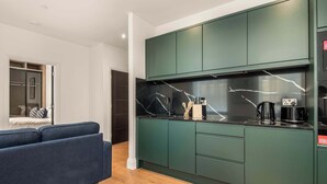 Una cocina moderna con armarios verde oscuro, salpicadero de mármol y una cafetera.