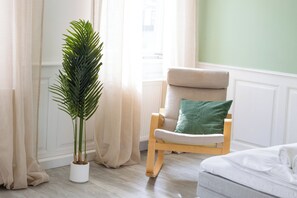 A room with a potted plant, a cushioned chair with a pillow, and a bed. - 140 sqm apartment for 6–10 people, large living/dining area & garage (Gernsbach)