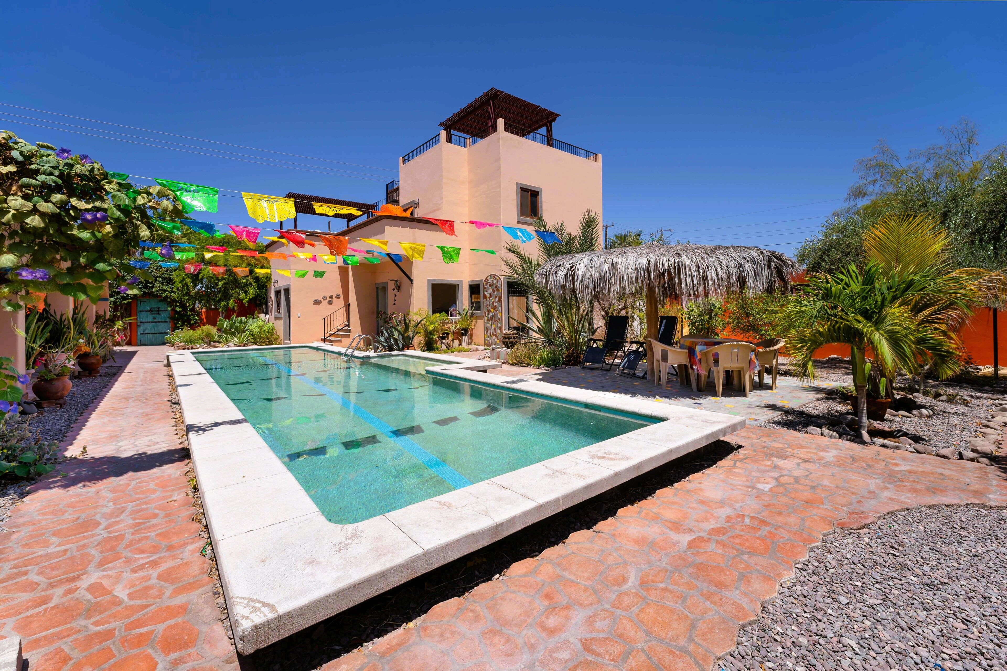 Una piscina con borde de piedra, rodeada por un patio con sillas y mesas.