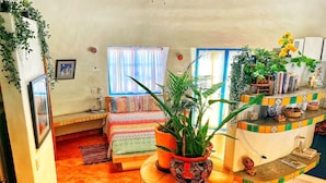A room with a bed, a small desk, a potted plant, and a shelf with books and decorative items. - dome suite domes (Loreto)