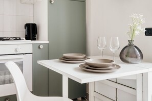A kitchen with a white table, a coffee maker, and a vase with flowers. - Hostmate - Milano - Volturno - Isola (Milan)