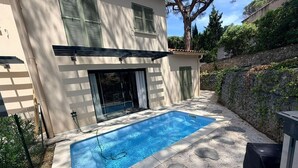A rectangular swimming pool with a clear blue water surface, surrounded by a concrete deck with circular indentations. - Villa Rosa By Avecoeur (Sainte-Maxime)