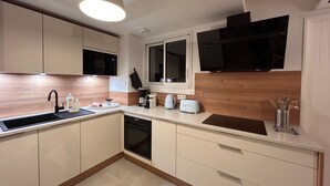 A compact kitchen with a sink, microwave, toaster, and a window above the counter. - Villa Rosa By Avecoeur (Sainte-Maxime)