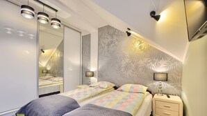 A bedroom with a bed, bedside tables, a mirror, and a wall with a leaf pattern. - Art Apartament Krynica Zdrój Centrum (Krynica-Zdrój)
