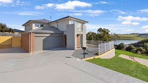 Ein modernes, zweistöckiges Haus mit Garage, einem eingezäunten Garten und Seeblick.