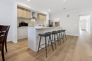 Uma cozinha moderna com ilha central, banquetas e armários de madeira.