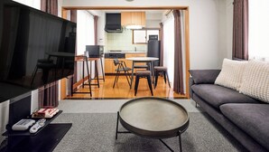 Ein modernes Wohnzimmer mit Flachbildfernseher, rundem Couchtisch und einer Couch.
