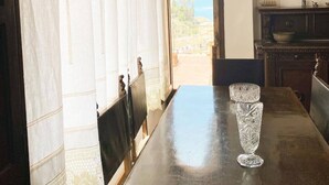 Ein Zimmer mit Blick durch einen Bogen, ein Tisch mit zwei klaren Glasvasen und eine dunkle Holzkommode.