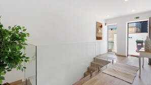 A modern interior with a glass railing, a staircase, and a plant. - ManuelHouse – Modern Two-Story Home in Vila Nova de Gaia (Vila Nova de Gaia)