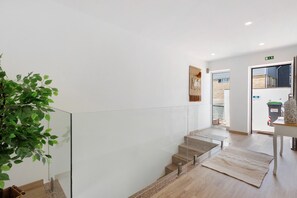 Un interior moderno con barandilla de vidrio, una escalera y una planta.