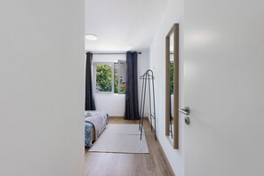 Una habitación con cama, lámpara de pie, ventana con cortinas y puerta.