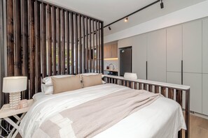 Une chambre moderne avec un grand lit, une table de chevet et une vue sur la cuisine.