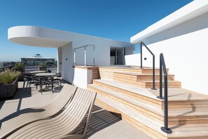 Une terrasse sur le toit avec une plateforme en bois, des sièges d’extérieur et une vue sur la ville.