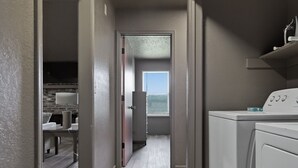 A laundry room with a washing machine, a dryer, and a countertop with a sink and mirror.