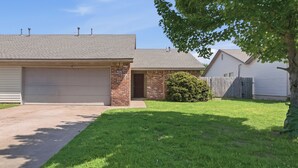 A residential house with a garage, a brick exterior, and a well-maintained lawn.