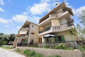 A multi-story residential building with balconies, a gated entrance, and a small outdoor seating area. - Abatis CityHome (Lefkada)