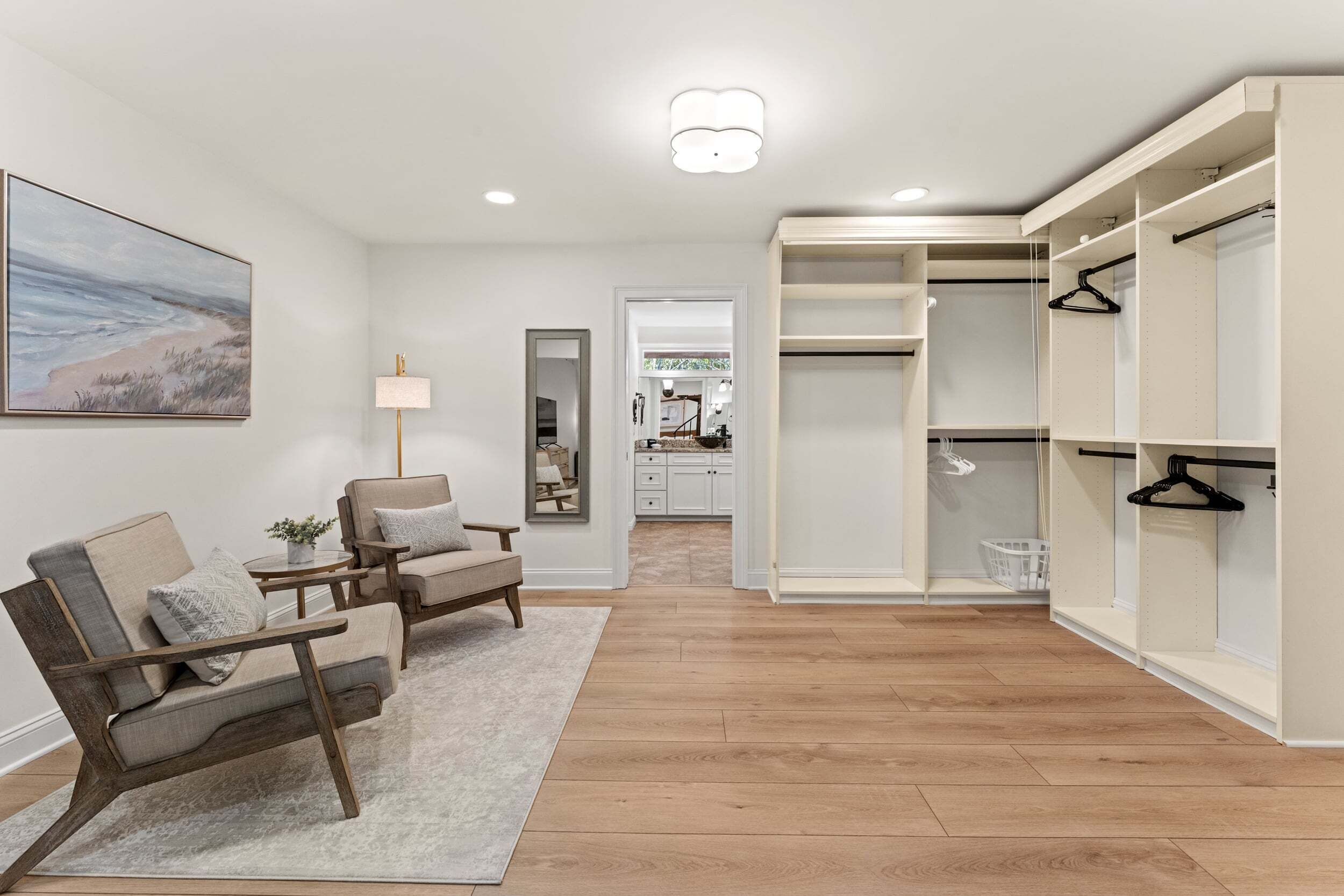 A room with a sofa, armchairs, a lamp, a painting, and a walk-in closet.