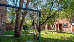 Um pátio com balanço, árvores e um edifício de pedra.