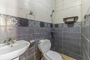 Kylpyhuone, jossa on pesuallas, wc, suihku ja kuviollisia laattoja.