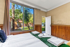 A bedroom with a large sliding glass door, a bed with white linens, and a green area rug. - Beautiful 7-bedroom hotel in tranquil Aghbalou perfect for groups (Ourika)