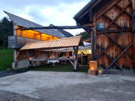 A rustic wooden building with a covered outdoor area, a staircase, and a small table with items on it.